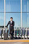 Traveler looking at cellphone next to row of luggage carts