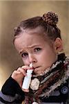 Young girl using nasal spray looking worried