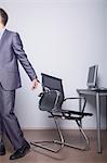 Businessman handcuffed to his office chair, walking away