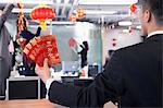 Businessman holding red envelopes and coworkers hanging decorations for Chinese new year