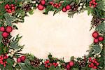 Christmas floral border with red bauble decorations, holly, ivy and mistletoe over old parhcment background.