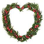 Christmas heart wreath with red bauble decorations, holly, mistletoe, ivy, pinecones and cedar leaf sprigs over white background.