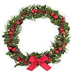 Christmas floral wreath decoration with baubles, red bow, holly, mistletoe and winter greenery over white background.