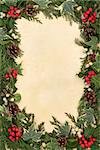 Traditional christmas and winter floral border of holly, ivy, mistletoe, fir and pine cones over parchment background.
