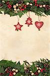 Christmas border with gold baubles, wooden red retro heart, star and tree decorations with holly, ivy and mistletoe on old parchment paper background.