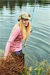 beautiful blond girl fishing in pond at autumn