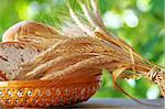 Basket of  bread , wheat spikes on table .