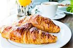 Breakfast with coffee and croissants in a basket on table