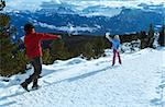 Family (mother with daughter) plays at snowballs on winter mountain slope