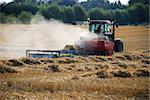 Red tractor baling straw in the countryside