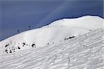 Off-piste slope and ropeway against blue sky. Caucasus Mountains. Georgia, ski resort Gudauri. Mt. Sadzele.