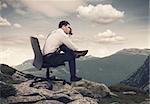 Young businessman sitting on chair and looking at landscape