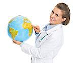 Smiling doctor woman pointing in earth globe