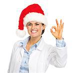 Happy doctor woman in santa hat showing ok gesture