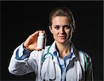 Doctor woman showing medicine bottle on black background