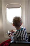 little boy sitting inside the plane and playing with his toy plane
