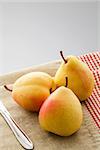 Three ripe pears on a linen napkin on a gray background