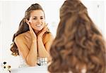 Happy woman checking facial skin condition in bathroom