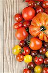 Border made from yellow, red and black tomatoes on wooden background