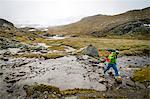 Hiker crossing mountain stream, Norway, Europe