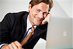 Smiling businessman sitting in front of laptop