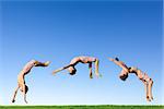 Young boy doing a backflip on a green meadow