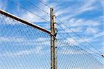 Mesh fence with barbed wire on a background of blue sky