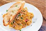 Seafood Spaghetti Pasta Cooked in Tomato Cream Sauce with Prawns Scallops White Fish Basil Bell Peppers and Bread Closeup