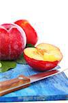 Ripe plums and knife on blue board.