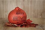 Happy Halloween inscription on the pumpkin, on wood surface