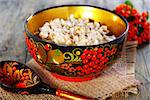 Pearl barley porridge in colorful bowl on a wooden table.