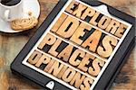 explore ideas, places and opinions - motivational words in vintage wood type on a digital tablet with a cup of coffee and cookie