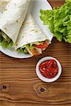 wheat tortilla with chicken and vegetables on plate on wooden table