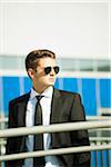 Young businessman wearing sunglasses, standing outdoors, Germany