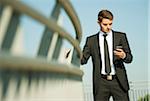 Portrait of businessman standing by railing and looking at smartphone, Germany