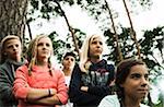 Portrait of group of children standing next to trees in park with arms crossed, looking forward in same direction, Germany