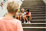 Backview of boy watching girls sitting on stairs outdoors, Germany