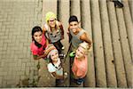 Group of children standing outdoors on cement staris, looking up at camera, Germany