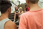 Backview of two boys talking to girls sitting on stairs outdoors, Germany