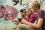 Group of children sitting on stairs outdoors, using tablet computers and smartphones, Germany