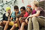 Group of children sitting on stairs outdoors, using tablet computers and smartphones, Germany