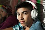 Close-up portrait of boy sitting next to wall outdoors, wearing headphones and looking at camera, Germany