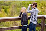 Young Couple using Binoculars on Lookout, Scanlon Creek Conservation Area, Bradford, Ontario, Canada