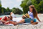 Three friends relaxing by Isar River, Munich, Germany