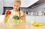 Girl balancing apples on broccoli scales