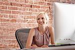 Portrait of mid adult woman at desk with brick wall