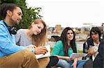 College students sitting outdoors with papers