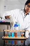 Chemistry teacher pouring chemicals into test tubes