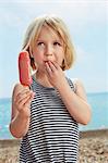 Child with fingers on lip holding ice lolly