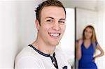 Close up portrait of young man with female in background